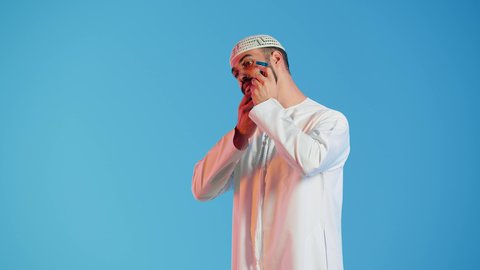 مفهوم العناية بالبشرة والنظافة ، الإهتمام المظهر الخارجي ، بورتريه  مقرب لرجل عربي خليجي اماراتي يرتدي الزي الاماراتي، يقوم بإزالة شعر الوجه بإستخدام شفرة الحلاقة ، شفرة حلاقة رجالية، خلفية ملونة