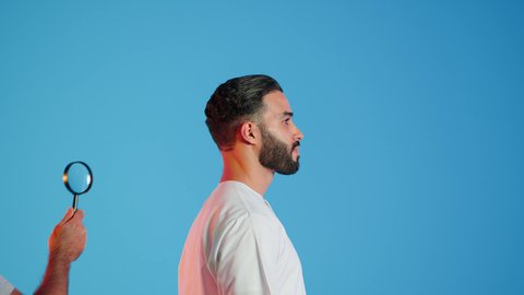 سلامة الشعر من القشرة والقمل، فحص فروة الرأس، المحفاظة على النظافة والمظهر الخارجي، بورتريه ليد تضع العدسة المكبرة على رأس شاب عربي اماراتي خليجي يرتدي الزي الاماراتي يقف باستقامة، خلفية ملونة