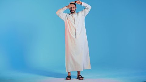 بورتريه لرجل عربي خليجي اماراتي يقوم بتصفيف شعره باستخدام فرشاة الشعر ( المشط ) بتعابير وإيماءات السعادة والسرور،،تمشيط وترتيب الشعر، مفهوم العناية والاهتمام بالجمال والأناقة والمظهر الخارجي، خلفية ملونة