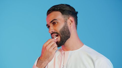 The concept of caring for and paying attention to dental health, dental equipment, a portrait of an Emirati Gulf Arab man wearing traditional Emirati attire using dental floss, daily dental hygiene, colorful background.