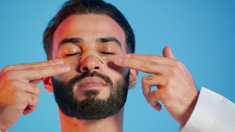 تجربة فاخرة باستخدام ماسكات تنظيف المسام ، منتجات تجميلية فعالة وتقنيات حديثة ، وعي الرجل العربي بأهمية العناية الشخصية، التخلص من الرؤوس السوداء والجلد الميت، مفهوم الاهتمام بنضارة وتحسين البشرة، بورتريه لرجل عربي خليجي اماراتي  يرتدي الزي التقليدي يضع لصقات الأنف ، خلفية ملونه .