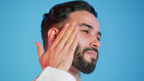 الاهتمام بالمظهر الخارجي ، استخدام مكونات تجميلية شبابية، مفهوم العناية بنضارة وتحسين البشرة، ترطيب وتنظيف وتفتيح الجلد، بورتريه لرجل عربي خليجي اماراتي  يرتدي االزي  التقليدي يمسك بيده كريم المرطب ويضعه على الوجه، خلفية ملونه