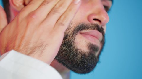 ترطيب وتنظيف وتفتيح الجلد، استخدام مكونات تجميلية شبابية، مفهوم العناية والإهتمام بنضارة وتحسين البشرة، بورتريه لرجل عربي خليجي اماراتي  يرتدي االزي  التقليدي يمسك بيده كريم المرطب ويضعه على الوجه، خلفية ملونه