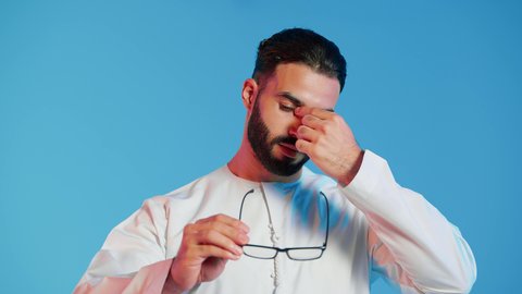 استخدام البصريات لتوضيح الرؤية،  بورتريه لرجل عربي إماراتي خليجي يرتدي الزي الإماراتي التقليدي, يمسك بيده نظاره طبيه, النظارة الطبية الخاصة بضعف النظر ، الرؤية من خلال النظارة الطبية ، مفهوم طول وقصر النظر ، خلفية ملونة