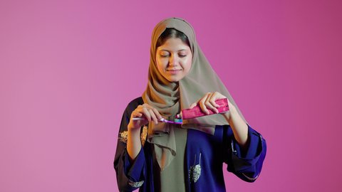 مفهوم العناية والإهتمام بصحة ونظافة الأسنان ، بورتريه مقرب لسيدة عربية خليجية اماراتيه تقوم بتنظيف الأسنان بفرشاة الأسنان ، روتين نظافة الفم اليومية ، تجنب تسوس الاسنان وامراض اللثة ، خلفية ملونة