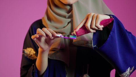 بورتريه مقرب لسيدة عربية خليجية اماراتيه  تقوم بتنظيف الأسنان بفرشاة الأسنان ، مفهوم العناية والإهتمام بصحة ونظافة الأسنان ، روتين نظافة الفم اليومية ، تجنب تسوس الاسنان وامراض اللثة ، خلفية ملونة