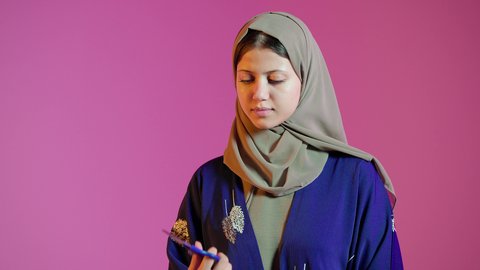 عدم القدرة على التوقف من الكلام، الاهتمام بالمظهر الخارجي والأناقة، مفهوم السكوت والصمت، بورتريه لامراه عربيه خليجيه اماراتيه ترتدي العباءة والحجاب تحمل بيدها مقص تنظر الى الكاميرا بتعابير الجدية، الوقوف باستقامة وثبات،  خلفية ملونة