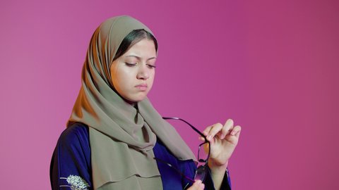 ماركات عالمية فاخرة، تحسين وتصحيح الرؤية، مفهوم ضعف النظر، بورتريه مقرب لسيدة عربية خليجية اماراتيه ترتدي العباءة والحجاب  تقوم باختيار نظارة ملائمة لملامح الوجه،  الاعجاب بالنظارات الطبية الجديدة، خلفية ملونة