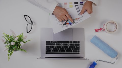 استخدام التقنيات الحديثة ، مصمم خليجي يعمل من خلال اللابتوب على مكتب أبيض, وظيفة ومهن سعودية, تصوير مقرب من الأعلى لرجل سعودي عربي لديه خبره بدرجات الألوان ,بيئة عمل  مكتبية, خلفية بيضاء .