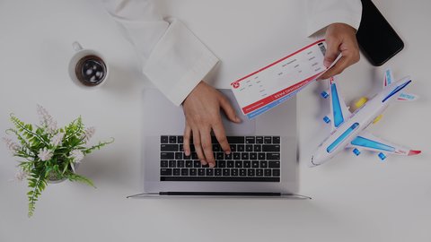 الاستمتاع بالمشروبات الساخنه ، تصوير مقرب من الأعلى لرجل خليجي سعودي يضع معلومات تذاكر الرحلات الى اللابتوب في المطار , بيئة عمل مكتبية , خلفية بيضاء .