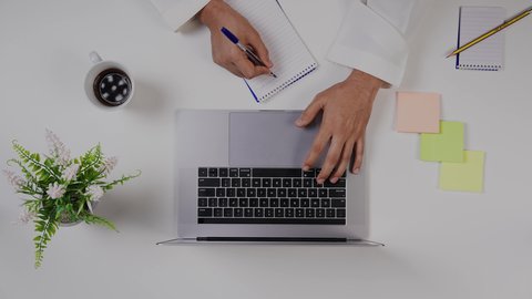 مهن ووظيفة سعودية ,الاستمتاع بالمشروبات الساخنه ،تصوير مقرب من الأعلى , ليد ولد  سعودي عربي يعمل من خلال اللابتوب على مكتب أبيض ,  بيئة عمل مكتبية , خلفية بيضاء .