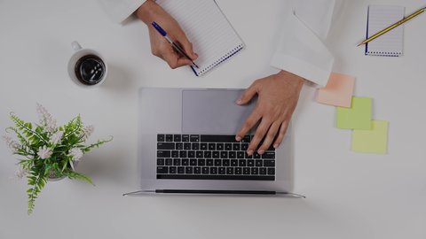 بيئة عمل مكتبية , الاستمتاع بالمشروبات الساخنه ،تصوير مقرب من الأعلى  ليد ولد  سعودي عربي يعمل من خلال اللابتوب على مكتب أبيض , مهن ووظيفة سعودية , خلفية بيضاء .