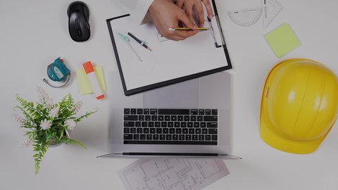 Saudi jobs and professions, an engineer working on designing buildings using a laptop on a white desk, a close-up shot from above of a Gulf architect, office work environment, white background.