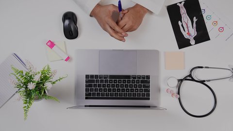 مفهوم الرعاية الصحية ،دمج التكنولوجيا بالطب، القطاع الطبي بالمملكة العربية السعودية, تصوير مقرب من الأعلى لطبيب خليجي سعودي يعمل على الحاسوب المحمول في العيادة, تقديم الاستشارات الطبية