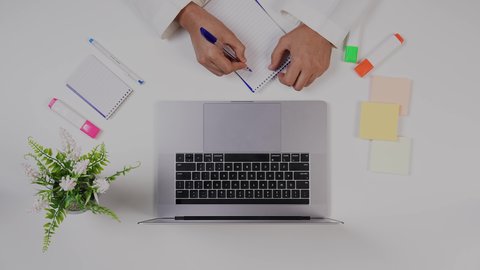 تصوير مقرب من الأعلى  ليد ولد سعودي عربي يعمل من خلال اللابتوب على مكتب أبيض , مهن ووظيفة سعودية , بيئة عمل مكتبية , خلفية بيضاء .