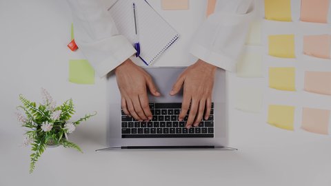 استخدام الحاسوب المحمول ، تصوير مقرب من الأعلى  ليد ولد سعودي عربي يعمل من خلال اللابتوب على مكتب أبيض , مهن ووظيفة سعودية , بيئة عمل مكتبية , خلفية بيضاء .