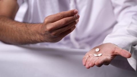 الآثار السلبية للادمان، تعاطي المواد السامة، القيام بعادات سلوكية ضارة، المعاناة من الاضطرابات النفسية والمشاكل الصحية، صورة مقربة لأيدي رجل عربي خليجي إماراتي يحمل مجموعة من الحبوب مخدرة