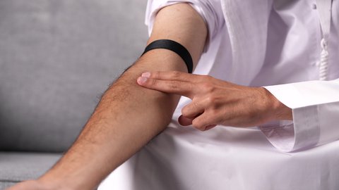 تعاطي المخدرات بالحقن في الأوردة، المعاناة من الاضطرابات النفسية والمشاكل الصحية، الآثار السلبية للادمان، القيام بعادات سلوكية ضارة وتعاطي المواد السامة، تصوير مقرب لرجل عربي خليجي إماراتي يرتدي الكندورة والغترة البيضاء يقوم بأخذ جرعة مخدرة