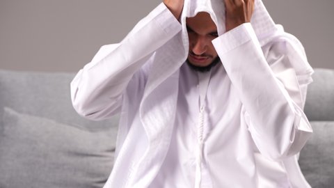 آلام الرأس المصاحبة للشعور بالصداع، تصوير مقرب لرجل عربي خليجي إماراتي يرتدي الكندورة والغترة يضع يده على رأسه بإيماءات التعب والإرهاق، تعابير الضجر والاكتئاب عند إيقاف التدخين، الأعراض الجانبية لسحب المواد المخدرة من الجسم