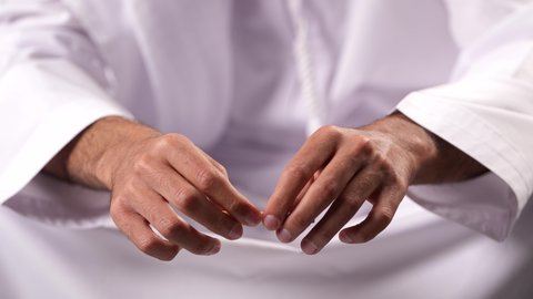 القيام بتصرفات سلوكية ضارة واستخدام المواد السامة، الأثار السلبية للادمان على التبغ والمخدرات، المعاناة من الاضطرابات النفسية والمشاكل الصحية، تصوير مقرب لرجل عربي خليجي إماراتي يرتدي الكندورة يقوم بحشو عقب السجائر