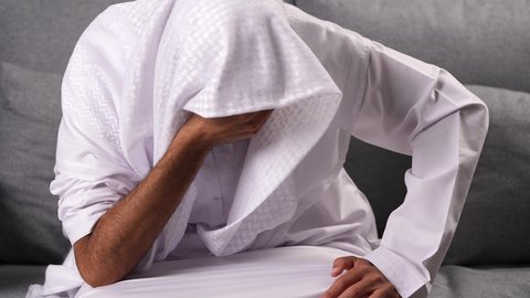 لوم الذات ومعاقبتها، عادات سلوكية ضارة وتعاطي مواد سامة، المعاناة من الاضطرابات النفسية والمشاكل الصحية، الادمان على التبغ والمخدرات، رجل عربي خليجي إماراتي يرتدي الكندورة يمسك راسة و يشعر بالالم