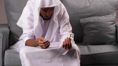 الادمان على التبغ والمخدرات، معاقبة النفس وتأنيب الضمير، المعاناة من الاضطرابات النفسية والمشاكل الصحية، رجل عربي خليجي إماراتي يرتدي الكندورة يمسك بيدة سيجارة حشيش، عادات سلوكية ضارة وتعاطي مواد سامة