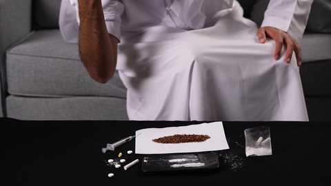 اتباع عادات سلوكية خاطئة، التعرض لفقدان الوعي نتيجة التعاطي، تصوير مقرب لايدي رجل عربي خليجي إماراتي يرتدي الكندورة يتعاطى جرعة كبيرة من المخدرات، المعاناة من الاضطرابات الجسدية والنفسية بسبب الإدمان