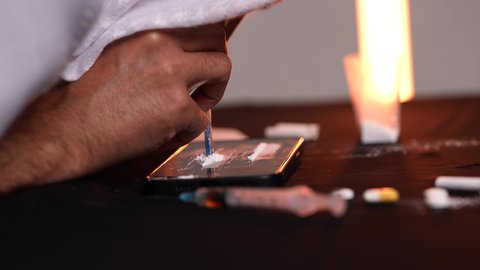 تعاطي المخدرات والمواد الكيميائية الضارة عن طريق الاستنشاق، المعاناة من الاضطرابات النفسية والمشاكل الصحية، الآثار السلبية للادمان، تصوير مقرب من الجانب لرجل عربي خليجي إماراتي يرتدي الكندورة والغترة يقوم باستنشاق المخدرات