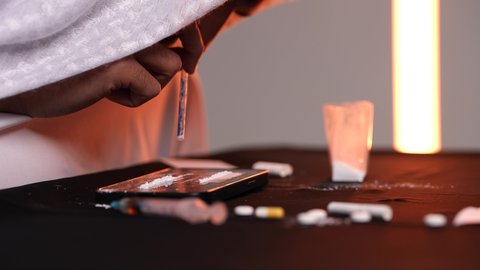 تعاطي المواد السامة عن طريق شمها، القيام بعادات سلوكية ضارة، المعاناة من الاضطرابات النفسية والمشاكل الصحية، الآثار السلبية للادمان، تصوير مقرب من الجانب لرجل عربي خليجي إماراتي يرتدي الكندورة والغترة يقوم باستنشاق المخدرات