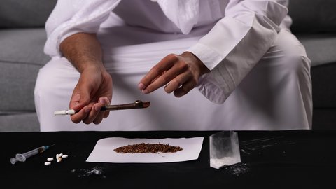 التبغ والمخدرات وأثرهما السلبي على الأداء الجسدي والعقلي، المعاناة من الاضطرابات النفسية والمشاكل الصحية، القيام بعادات سلوكية ضارة وتعاطي المواد السامة، تصوير مقرب ليد رجل عربي خليجي إماراتي يقوم باشعال عقب السجائر