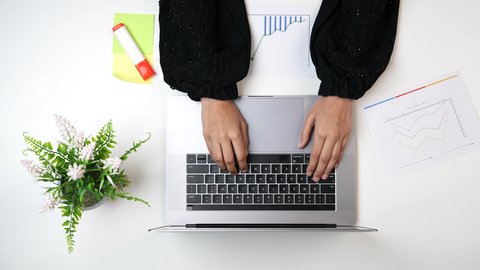 النقر على شاشة الحاسب المحمول, استخدام التقنيات الحديثة ، مصممة خليجية تعمل من خلال اللابتوب على مكتب أبيض, وظيفة ومهن سعودية, تصوير مقرب من الأعلى لامراة عربيه خليجيه سعودية لديها خبره بدرجات الألوان ,بيئة عمل مكتبية, خلفية بيضاء