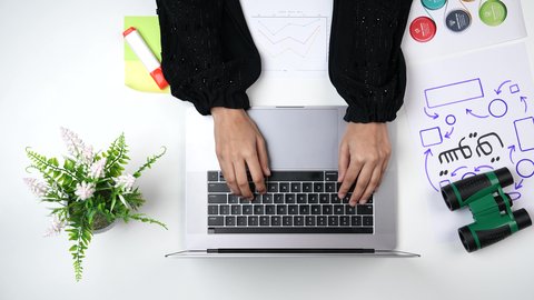 مسوقة خبيرة تعمل من خلال اللابتوب على مكتب أبيض , تصوير مقرب من الأعلى لامراة عربية سعودية لديها خبره بإدارة الأعمال , وظيفه ومهن سعودية , بيئة عمل مكتبية , خلفية بيضاء