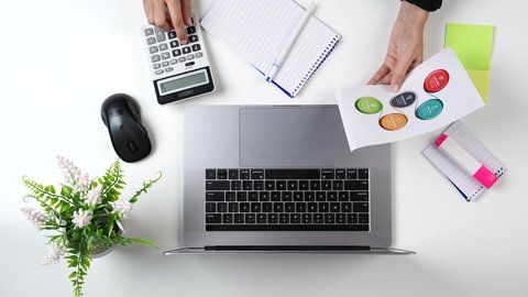 تصوير مقرب من الأعلى لامراة عربية سعودية لديها خبره بالمحاسبة تعمل  من خلال اللابتوب على مكتب أبيض , وظيفه ومهن سعودية , بيئة عمل مكتبية, خلفية بيضاء .