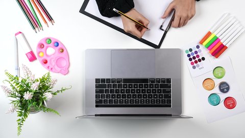 ادوات ومعدات التلوين، نشاطات ترفيهية فنية، تصوير مقرب من الاعلى ليد امراة عربية خليجيه سعودية تقوم بالرسم على اللوحة امام الحاسب المحمول، التعلم والابداع وتنمية المهارات