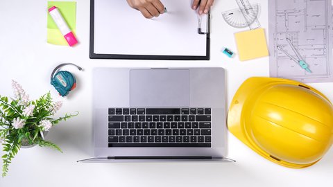 تدوين الأفكار والملاحظات, بيئة عمل مكتبية, مهندسة تعمل على تصميم العمارات من خلال اللابتوب على مكتب أبيض, وظيفه ومهن سعودية ,تصوير مقرب من الأعلى لمهندسة معمارية خليجية , خلفية بيضاء