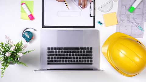 مهندسة تعمل على تصميم العمارات من خلال اللابتوب على مكتب أبيض, وظيفه ومهن سعودية , تدوين الملاحظات الهامه ,تصوير مقرب من الأعلى لمهندسة معمارية خليجية ,بيئة عمل مكتبية , خلفية بيضاء