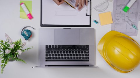 تدوين الملاحظات الهامه, وظيفه ومهن سعودية , مهندسة تعمل على تصميم العمارات من خلال اللابتوب على مكتب أبيض ,تصوير مقرب من الأعلى لمهندسة معمارية خليجية ,بيئة عمل مكتبية , خلفية بيضاء