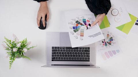 تنفيذ مهام التصميم عبر الحاسوب المحمول, استخدام التقنيات الحديثة ، مصممة خليجية تعمل من خلال اللابتوب على مكتب أبيض, وظيفة ومهن سعودية, تصوير مقرب من الأعلى لامراة سعودية عربية خليجيه لديها خبره بدرجات الألوان ,بيئة عمل مكتبية, خلفية بيضاء