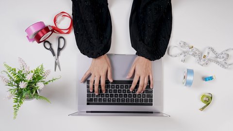 العمل فى المكتب , مصممة أزياء خليجية سعودية تقوم بالنقر على لوحة مفاتيح اللابتوب , مصممة أزياء مبتكرة , مهنة ووظيفه سعودية , معدات الخياطة , تصميم ورسم الأزياء عن طريق اللابتوب