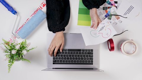 The use of modern technologies, a Gulf designer working on a laptop at a white desk, Saudi jobs and professions, a close-up shot from above of the hand of an Arab Gulf Saudi woman with experience in color gradients, office work environment, white background.