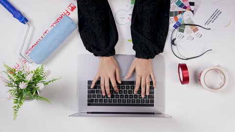 Saudi jobs and professions, a Gulf designer working on a white desk with a laptop, using modern technologies, a close-up shot from above of the hand of an Arab Gulf Saudi woman with experience in color gradients, office work environment, white background.