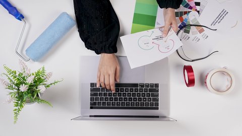 مصممة خليجية تعمل من خلال اللابتوب على مكتب أبيض, استخدام التقنيات الحديثة , وظيفة ومهن سعودية, تصوير مقرب من الأعلى ليد امراة عربية خليجيه سعودية لديها خبره بدرجات الألوان ,بيئة عمل مكتبية, خلفية بيضاء