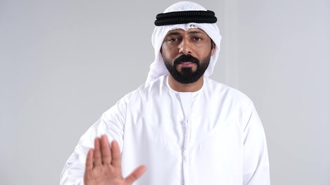 الامر بالتوقف عن فعل شيء ما, تعابير الموافقة و القبول, بورترية مقرب لرجل عربي خليجي اماراتي يرتدي الكندورة و الغتره ينظر الى الكاميرا  يرفع أصبع الإبهام الى أعلى, ايماءات السعادة و السرور, خلفية بيضاء