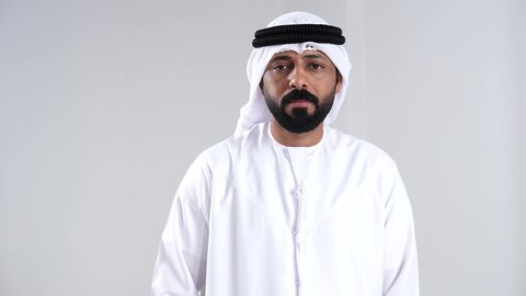 الشعور بالإنزعاج والغضب, الامر بالتوقف عن فعل شيء ما, تعابير الرفض والإمتناع، بورتريه مقرب لرجل عربي خليجي اماراتي يرتدي الكندورة و الغتره يرفع يدية بإيماءات النهي، خلفية بيضاء
