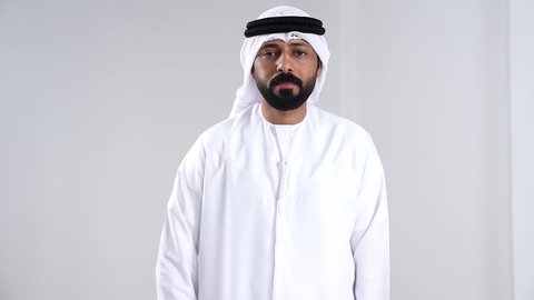 تعابير الرفض والإمتناع، الامر بالتوقف عن فعل شيء ما، الشعور بالإنزعاج والغضب، بورتريه مقرب لرجل عربي خليجي اماراتي يرتدي الكندورة و الغتره يرفع يدية بإيماءات النهي، خلفية بيضاء