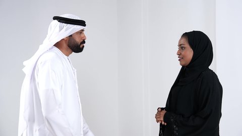 تبادل الأحاديث بين الزوجين, أجواء عائلية مليئة بالحب، الحياة لزوجية الناجحة، مفهوم الترابط الأسري، بورتريه من الجانب لرجل عربي خليجي اماراتي يرتدي الكندورة و الغتره يقوم بالتحدث مع زوجته، ايماءات السعادة و السرور, خفية بيضاء