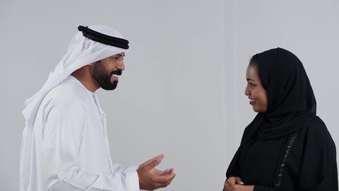 دردشة ومحادثات عائلية, أجواء عائلية مليئة بالحب، الحياة لزوجية الناجحة، مفهوم الترابط الأسري، بورتريه من الجانب لرجل عربي خليجي اماراتي يرتدي الكندورة و الغتره يقوم بالتحدث مع زوجته، ايماءات السعادة و السرور, خفية بيضاء