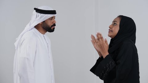 ازمة في العلاقات الاسرية, سوء تفاهم , شجار بين الزوجين, بورترية لزوجان عربيان خليجيان امارتيان يرتديان الزي التقليدي يتجادلان مع بعضهم ، مشاكل عائلية ، صراع اسري  ، خلفية بيضاء