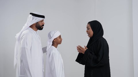 مفاهيم التربية الأسرية والعلاقات العائلية, نقاش أسري بين الام والابن, بورتريه لام عربيه خليجيه اماراتية ترتدي العباءه و الحجاب تقوم بنصح ابنها برفقة والده، ولد عربية خليجي اماراتى يرتدي العمامة يقوم بالتحدث مع والدته, خلفية بيضاء