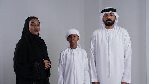 The essentials of a happy Emirati family, owning a private home, commitment to family rules and laws, a portrait of an Emirati Gulf Arab boy wearing a kandura and ghutrah holding the key to the new house alongside his parents, gestures indicating happiness and joy, white background.